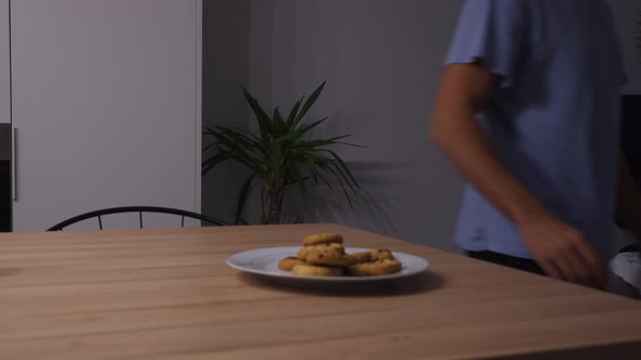 Man walking past a plate of cookies and eating all of them, concept for cravings and hunger