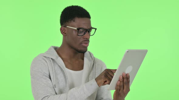 African Man Reacting to Loss on Tablet on Green Background