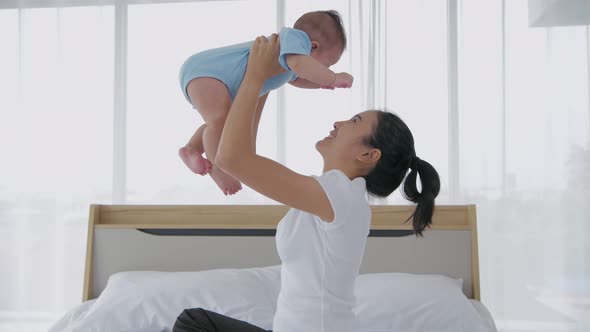 Family concept. Mother playing with baby in the bedroom