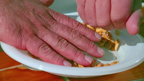 Close-up of a man's hand taking beautiful roasted peanuts.