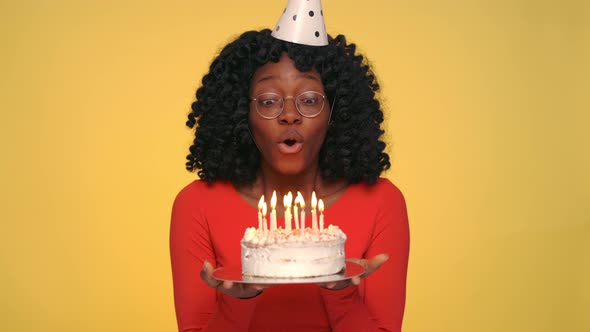 Happy Woman Making Wish and Blowing Out Candles on Cake