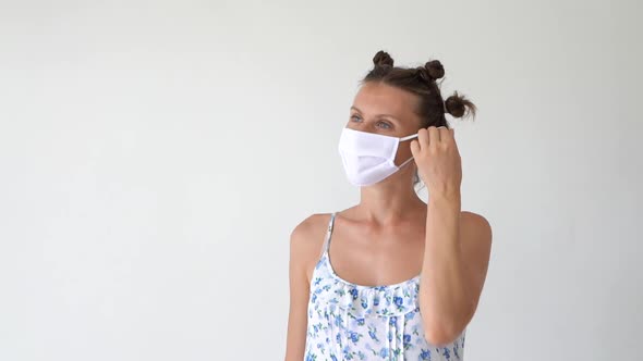 Young woman takes off medical mask and smiling looking at camera.