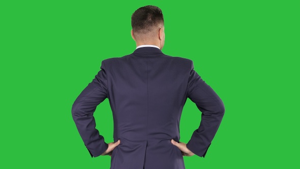 Businessman looking around with hands on hips on a Green