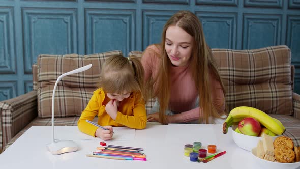 Lovely Mother Babysitter Teacher Helping Kid Daughter with Homework Learning Writing at Home