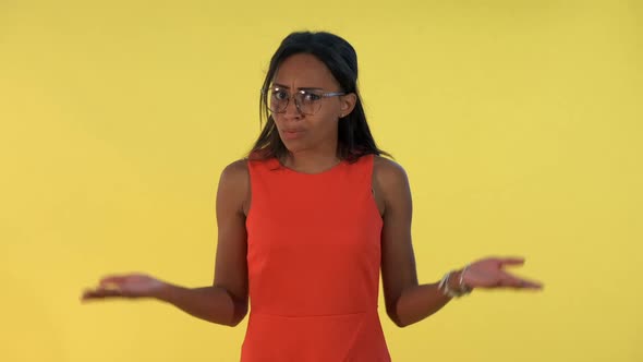 Mixed-race Young Woman Spreading Her Hands To the Sides and Saying "What" on Yellow Background