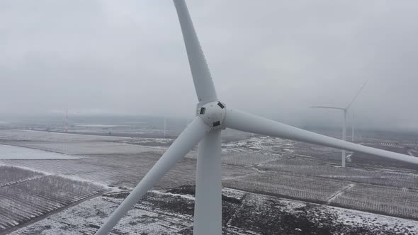 Wind turbine in a snowy landscape with early winter morning mist.