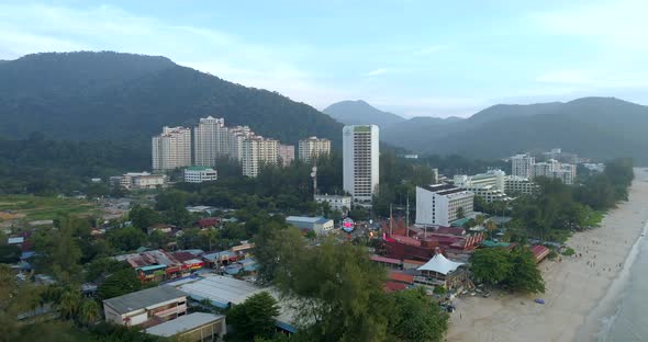 A uplifting drone shot of the beach and town of Batu Feringghi in Penang, Malaysia.