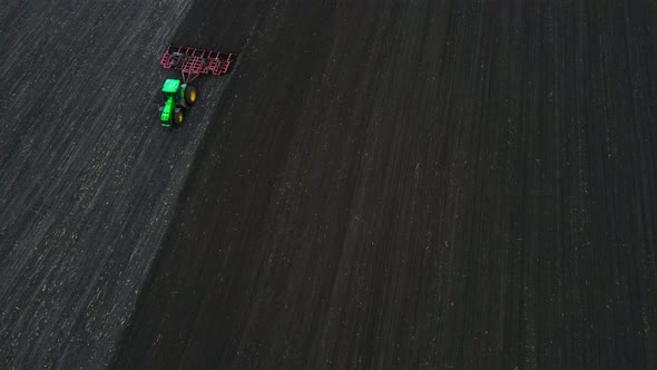 Aerial view of a modern green tractor seeding agricultural field