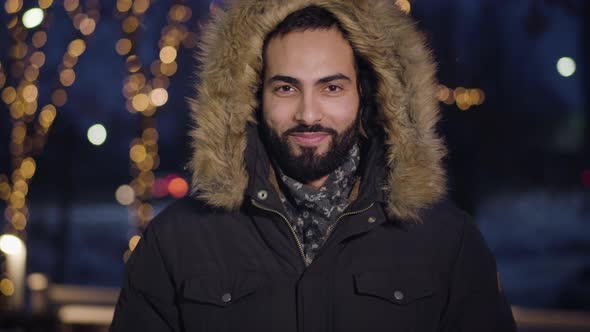 Portrait of Joyful Middle Eastern Man Looking at Camera and Smiling When Getting Snowball in Face