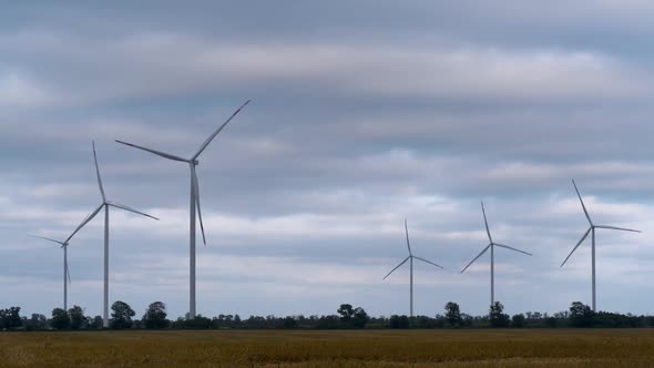 Windmill Turbines Rotating Propellers in Time Lapse Against Sunset Cloudy Sky in the Evening