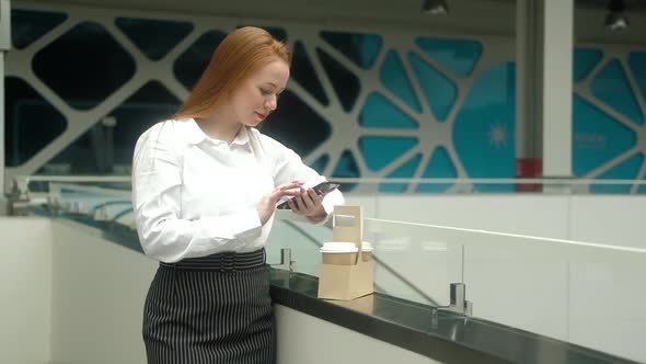 adult business woman with a cup of coffee uses the phone in the office