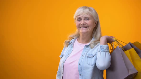 Joyful Retiree Lady Showing Shopping Bags and Golden Card, Standing Customer