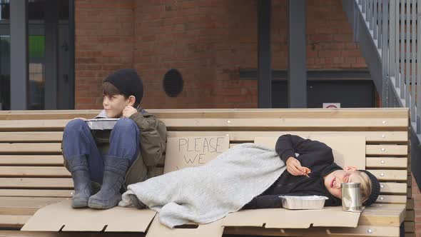 Homeless Kids Eating Outdoors and Looking Away at Strangers