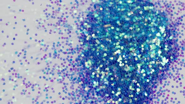 Blowing Out Blue Glitter on White Background Gloss Powder Closeup