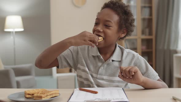 Kid Snacking on Waffles Doing Homework