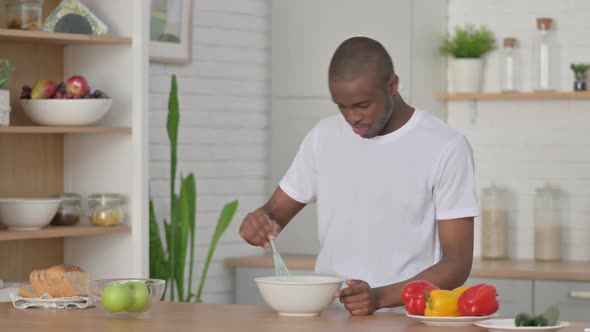 Healthy African Man Focused While Cooking in Kitchen