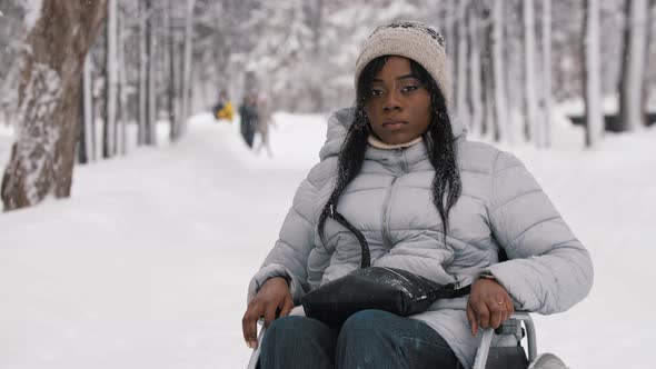 Sad Black Woman Sitting in a Wheelchair in Winter Forest