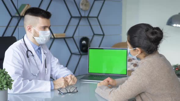 Professional male doctor filling out data, making medical reports on computer with green screen