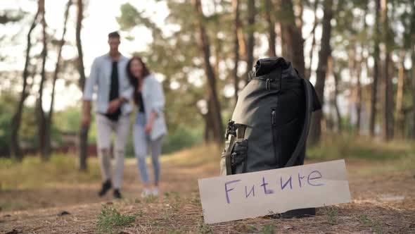 Future Banner at Backpack in Autumn Forest and Blurred Couple Passing Leaving at Background