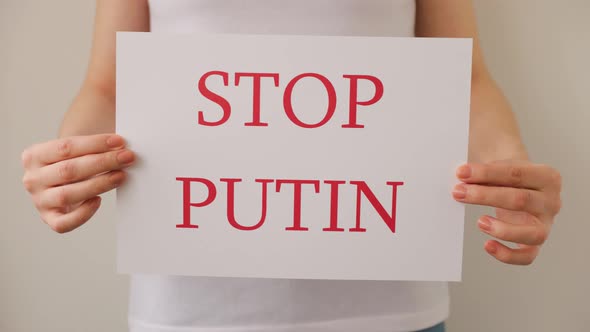 Close Up of a Protester Hands Holding Cardboard Banner with the Words Stop Putin