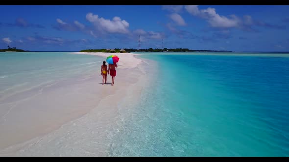 Two people in love on tranquil lagoon beach holiday by blue water with white sandy background of the