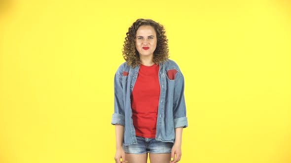 Curly Female Making a Rock Gesture, Enjoying Life and Laughing on Yellow Background at Studio