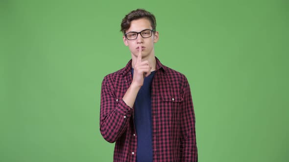 Young Handsome Teenage Nerd Boy with Finger on Lips