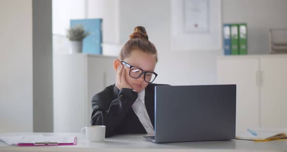 Portrait of Little Girl Sitting at Workplace Using Laptop