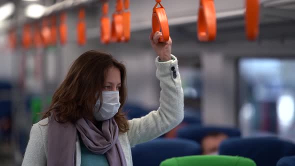 Middle-aged Woman Rides Public Transport. She's on a City Train. She's Wearing a Protective Mask
