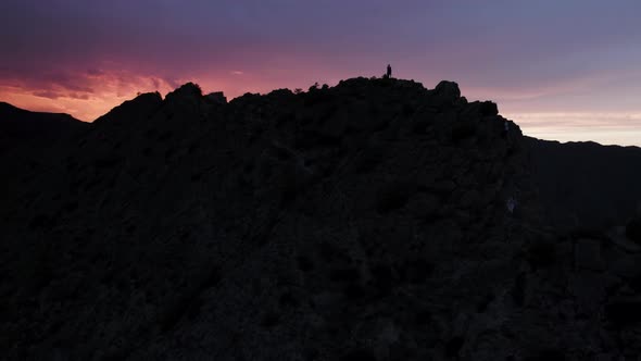 Silhouettes of people doing yoga in mountains at sunrise