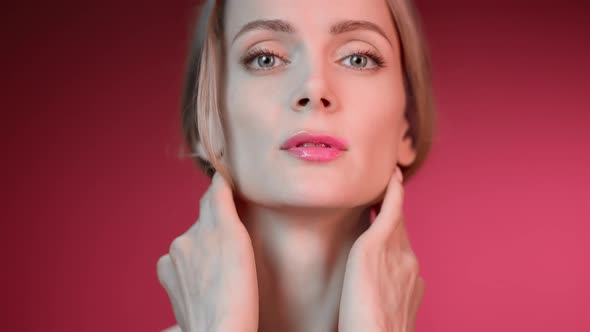 Portrait of Pretty Young Blonde Lady with Perfect Clean Moisturizing Skin Isolated on Pink Turn Up