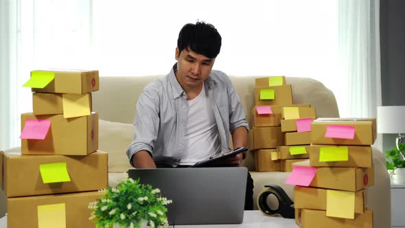 man entrepreneur checking product order with laptop computer and writing for delivery to customer