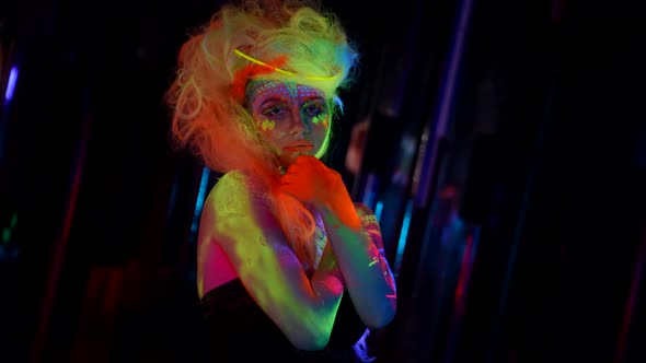 Fluorescent Cosmetic is Glowing in Darkness Model with Bright Paints on Skin and Hair
