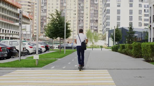 Back View of Businessman Riding Electric Scooter in City