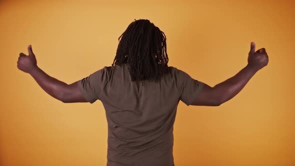 Back View of African American Black Man with Thumbs Up Isolated on Orange Background