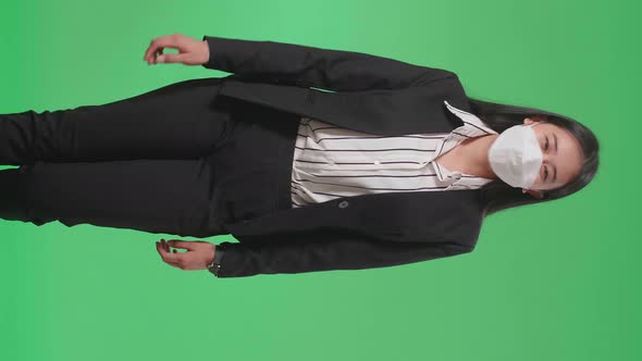 An Asian Business Woman Wearing Mask Walking In Front Of Green Screen In The Studio