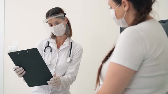 Doctor in Mask Providing Consultation for Pregnant Woman