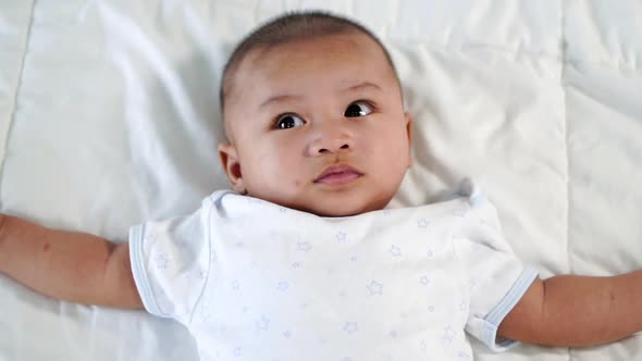 slow-motion of baby lying on a bed at home