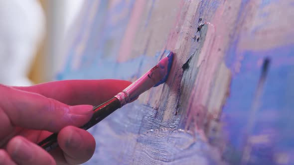 Paint Artist Drawing an Abstract Painting in Blue and Lavender Tones with a Brush and Oil Paints