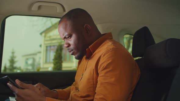 Serious Male Entrepreneur Working in Car Backseat