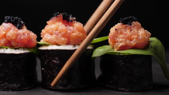 Take One Sushi Roll From Black Slate Board Using Chopsticks