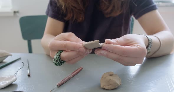 Woman Making Doll Ceramic Part. Female Sitting and Creating Ear for Doll at Home at Table. Pottery