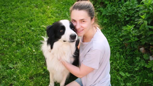 Smiling Young Attractive Woman Stroking Playing with Cute Puppy Dog Border Collie on Summer Outdoor