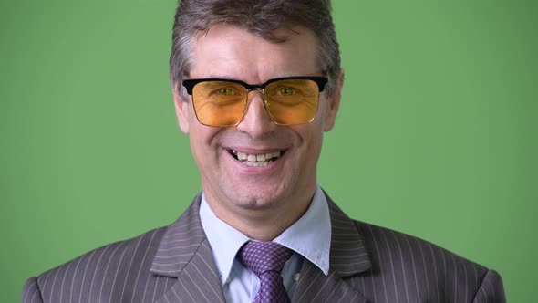 Mature Handsome Businessman Against Green Background