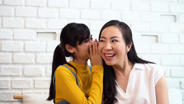 Asian Family of Teenage Girl Gossiping at Mature Woman's Ears at Home