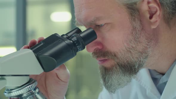 Mature Scientist Working with Microscope