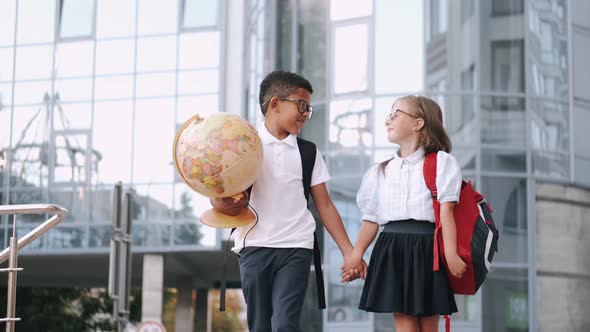African American Boy and Girl with Backpacks and Globe Go To School