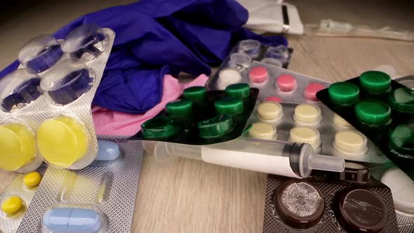 Doctor Hand Puts Vial with Liquid on Table Against Pills