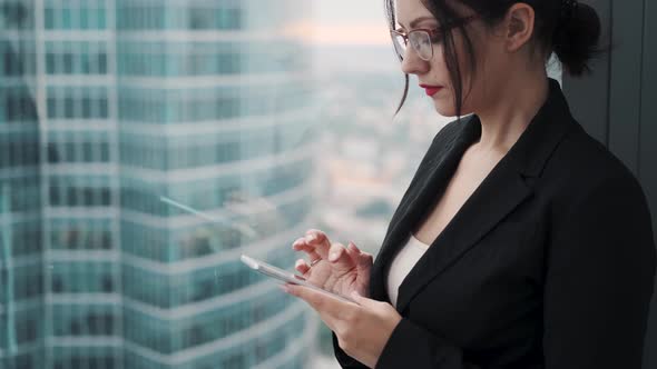 Young Woman in Business Suit Uses a Smartphone. Portrait of a Business Woman on the Background