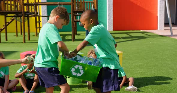 Side view of Caucasian female teacher teaching schoolkids about bottle recycle in the school playgro